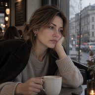 Женщина в кафе у окна подпирает щёку рукой